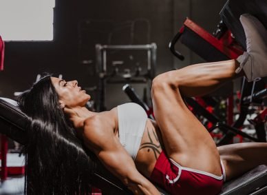 Woman bodybuilder with brown hair using leg press machine, Fitness coach